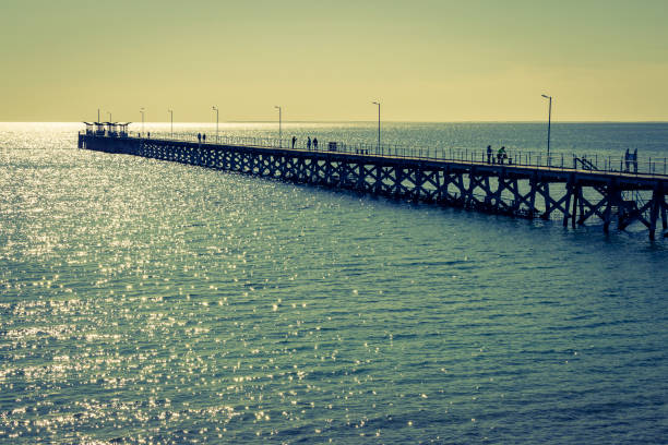 Smoky Bay Jetty in shimmering back lighting with unrecognisable people in silhouette (Eyre Peninsula, South Australia)