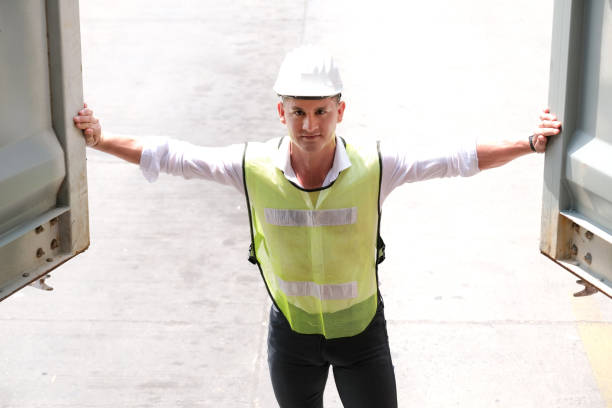 istock Inspector worker who wears a safety helmet and vest opens the container and checking the quality of cargo. Unload and loading product and transfer to the warehouse. Industrial and logistic concept. 1276439142