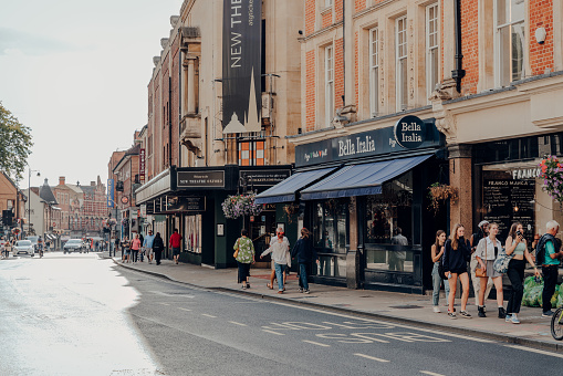 Oxford, UK - August 04, 2020: People walking past restaurants on a street in Oxford, a city in England famous for its prestigious university, established in the 12th century.