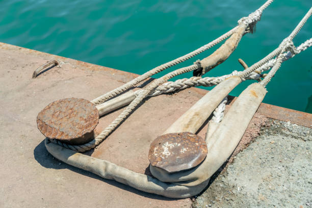 Shore bits with white ropes. Close up view of a steel bollard in a dock with mooring lines. Old kneeling on the pier. Shore bits with white ropes. Close up view of a steel bollard in a dock with mooring lines. Old kneeling on the pier. wharfe river photos stock pictures, royalty-free photos & images