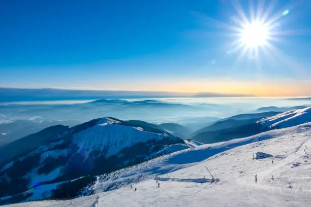 Photo of Ski Slope and Winter Sun over Mountain Peaks