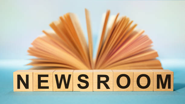 Open book and Wooden cubes with the abbreviation NEWSROOM stock photo