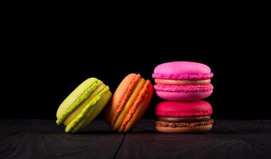 Heap of french colorful macaroon on wooden table isolated on black background with clipping path