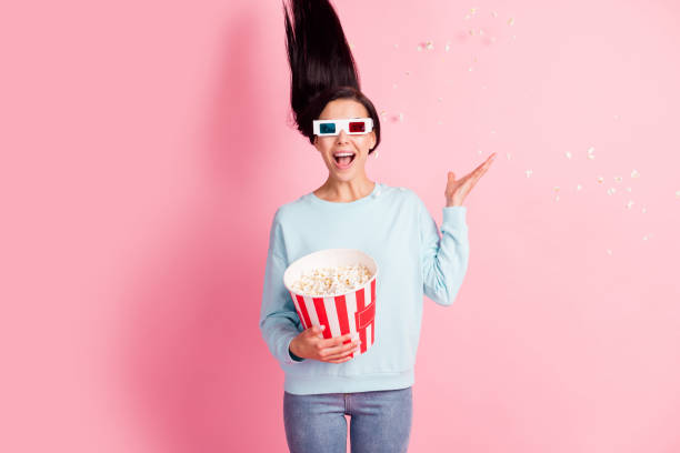 istock Crazy lady throwing pop corn up watch movie 3d spectacles wear pullover jeans isolated pink color background 1276443786
