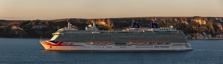 Weymouth Bay, United Kingdom - July 6, 2020: Beautiful panoramic shot of P&O cruise ship Britannia anchored in Weymouth Bay at sunset