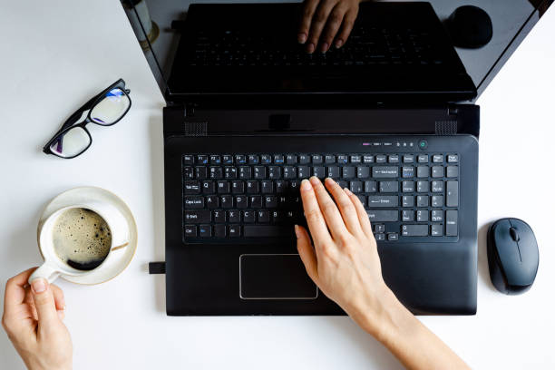 Top view of black laptop and girls hands sitting on white background with coffee, work from home or cafe