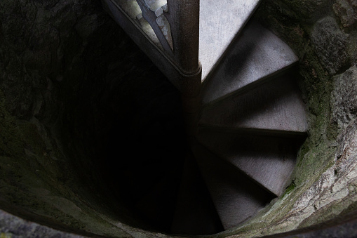 Top view of spiral staircase leading from light into darkness. Going towards the unknown, fear, afraid concepts