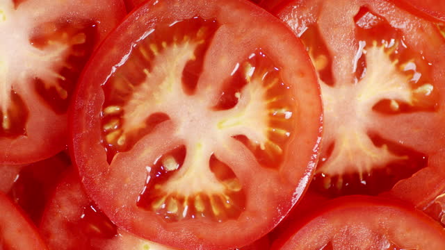 Slices of ripe tomato rotate slowly.