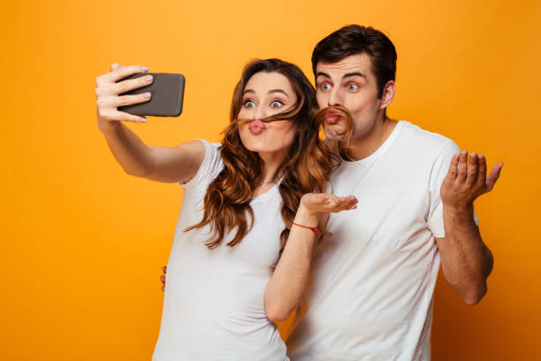 istock Funny young lovely couple having fun together while making selfie 1276448334
