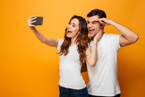 istock Cheerful young lovely couple posing together while making selfie 1276448776