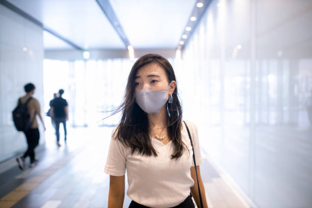 istock Young woman with protective face mask walking in city 1276451240