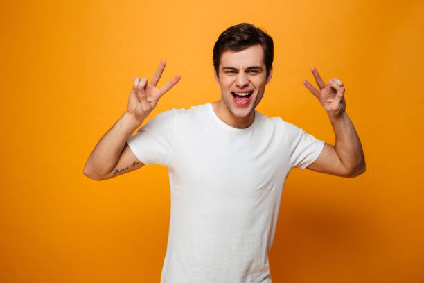 istock Joyful man in t-shirt showing peace gestures 1276451693