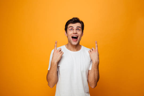 istock Surprised happy man in t-shirt pointing and looking up 1276451860
