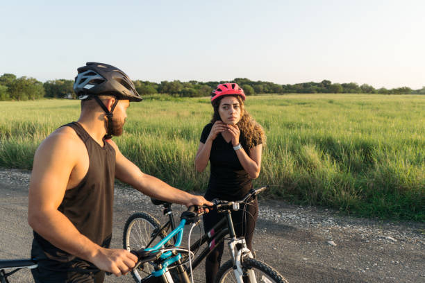 istock Latin man holding woman's bike while she attaches helmet 1276453441