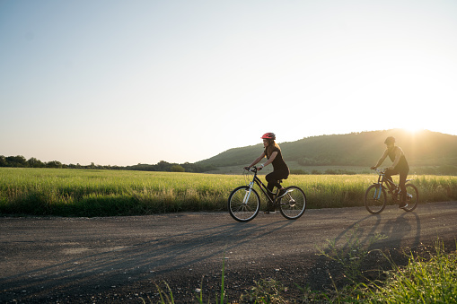 A young latin couple cycling on a road in the countryside and looking ahead.