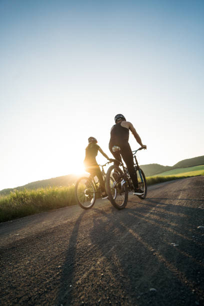 istock Back view of couple riding bikes in countryside 1276453453