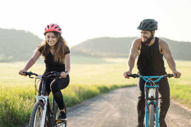 istock Fun couple riding bikes together in countryside 1276453470