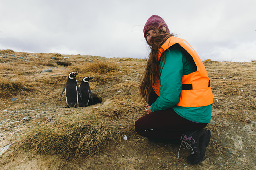 Woman traveler with long hair in life jacket have an Antarctic expedition, exploring the Magellanic Penguins on the remote island in Patagonia Chile