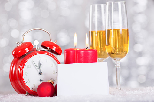 Christmas and New Year decoration - champagne glasses, Christmas tree ornaments and a clock with colorful glitter background.