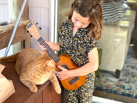 A girl playing music for her kitten