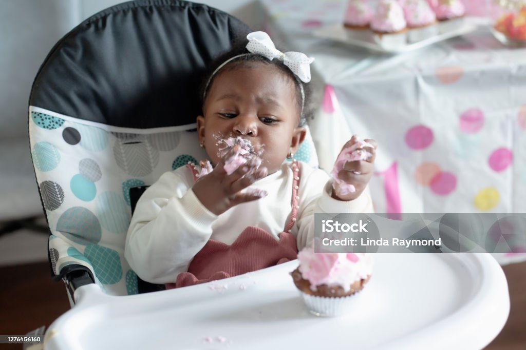 Cute baby girl eating birthday cake birthday cake, one baby girl birthday cake, dirty Baby - Human Age Stock Photo