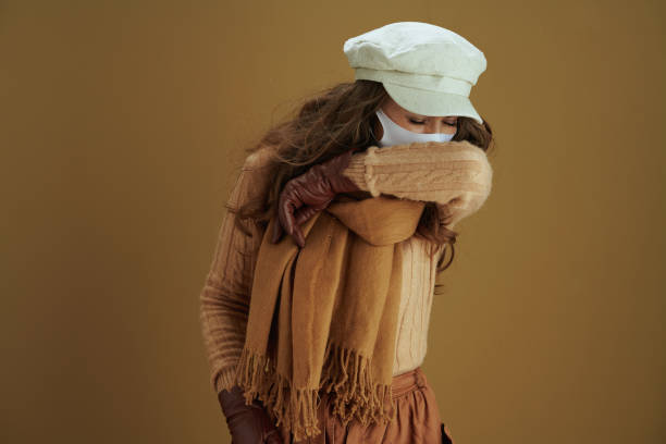 istock young woman sneezing into elbow isolated on beige background 1276461206
