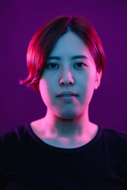 portrait of young woman lit by neon colored lights - vertical bright brightly lit vibrant color imagens e fotografias de stock