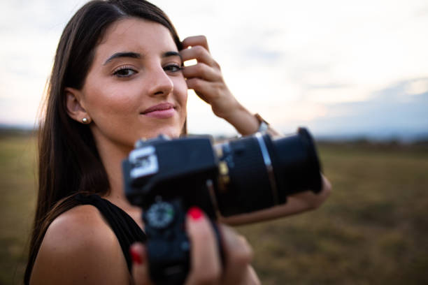 A pretty young woman holding a camera smiling