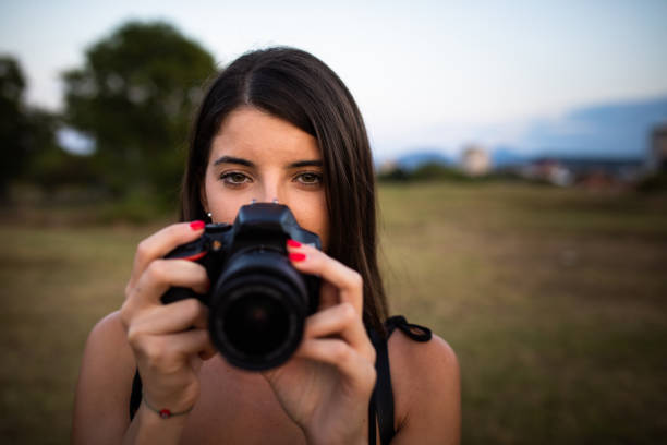 istock A young woman with beautiful eyes looking at the camera while holding a camera in front of her face 1276466221