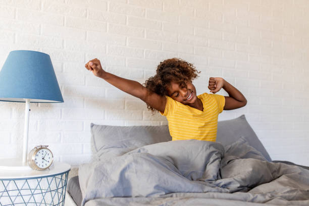 Young African American girl waking up Young girl laying in bed and stretching waking up stock pictures, royalty-free photos & images