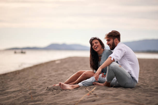istock Young lovers sitting on the beach 1276471119