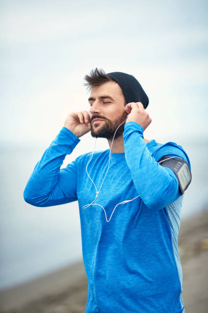 istock Young jogger enjoying music running on the beach 1276473071