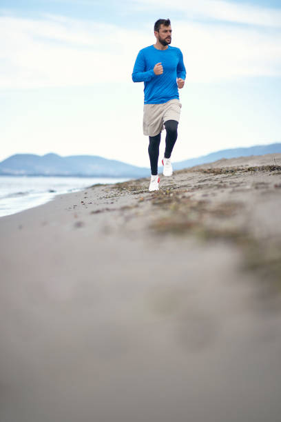 istock Young man jogging on the beach 1276473217