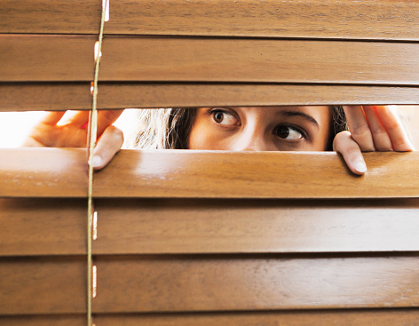 Young woman peers out of a window.