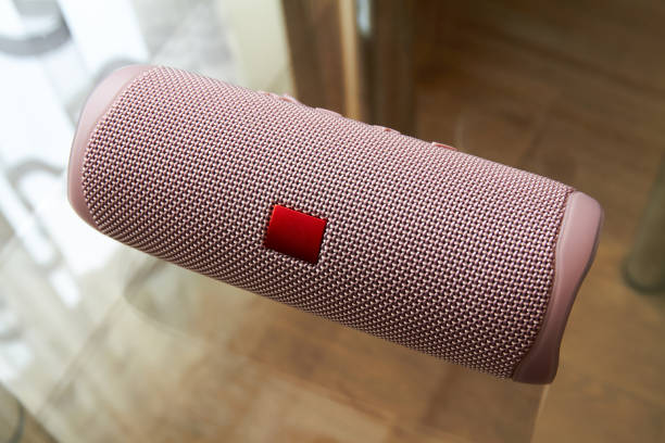Portable pink bluetooth and wireless speaker on a glass surface