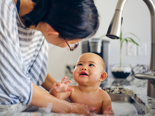 bebé tomando un baño de fregadero de cocina - baños térmicos fotografías e imágenes de stock