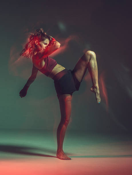 istock Cool female fighter training flying knee in studio in neon light. Motivation concept. Long exposure shot 1276483768
