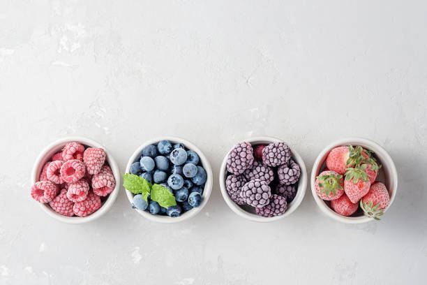 Frozen berries in small bowls on a concrete background from copies of space. Frozen berries in small bowls on a concrete background from copies of space. frozen stock pictures, royalty-free photos & images