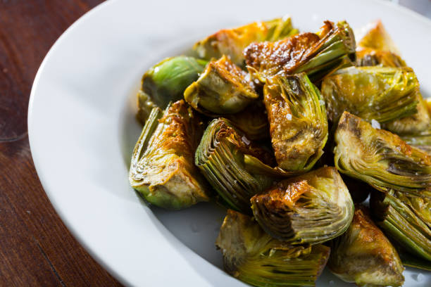 istock Delicious fried artichoke halves on a white plate 1276486315