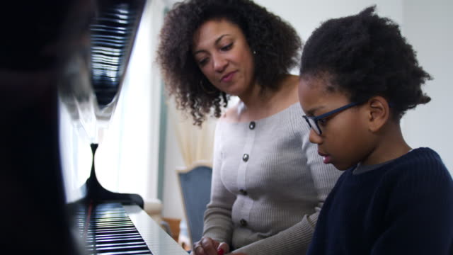 Young Boy Learning To Play Piano Having Lesson From Female Teacher