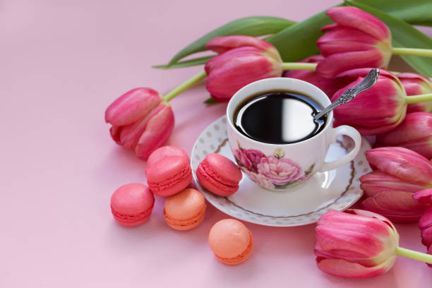istock Cup of coffee with macaroons and tulips on a pink background. 1276488751