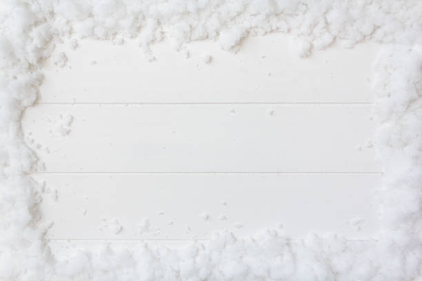 Top view of snow frame on white wooden background with copy space. Christmas or winter background