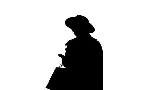 Medium shot. Front view. Smiling African american fashion girl in coat and black hat texting on her phone, Alpha Channel Professional shot in 4K resolution. 046. You can use it e.g. in your medical, commercial video, business, presentation, broadcast