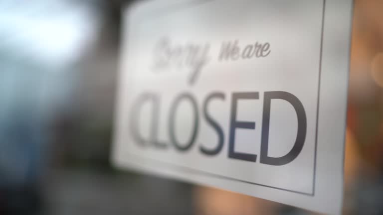 Business owner turning to closed sign on storefront door