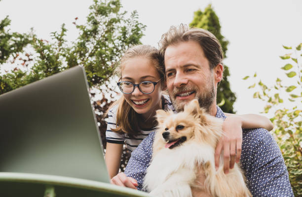 istock Caucasian father, daughter and dog having video chat on laptop computer 1276490531