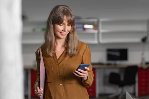 istock Happy Businesswoman Using Mobile Apps on her Smartphone at Work 1276491081