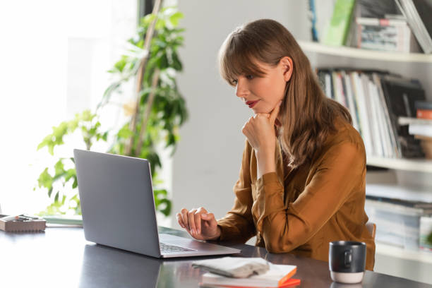 istock Businesswoman Wearing a Yellow Shirt Using a Laptop Computer at Work 1276491132
