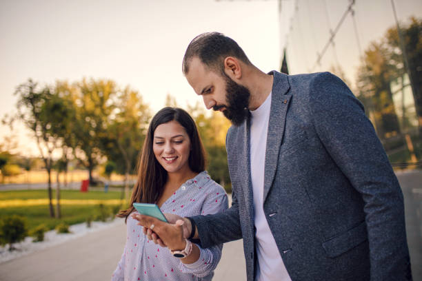 istock Two young business people using phone outdoors 1276494193