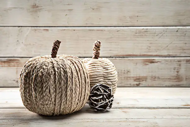 This is a close up photo of white tweed  pumpkins on a wood textured background. There is space for copy. This image would work well for autumn, fall, Thanksgiving and a holiday Halloween season in the fall.