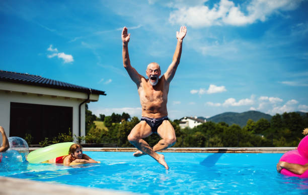 gruppe von fröhlichen senioren im schwimmbad im freien im hinterhof, springen. - active seniors retirement enjoyment swimming pool stock-fotos und bilder